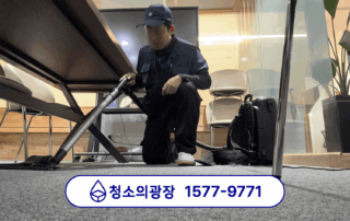 난방 전 사무실 대청소 중 회의실 테이블 아래 카펫을 청소하는 모습